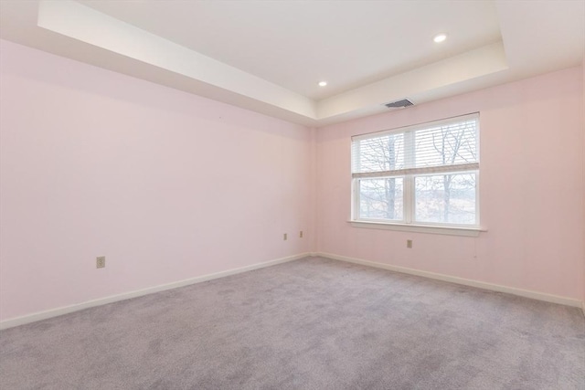 carpeted empty room with a tray ceiling