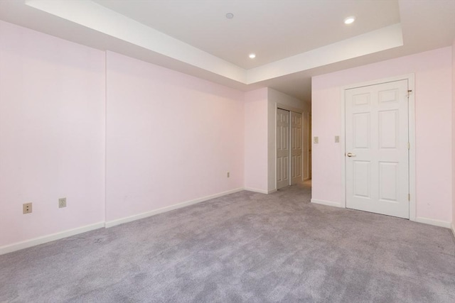 carpeted spare room featuring a tray ceiling