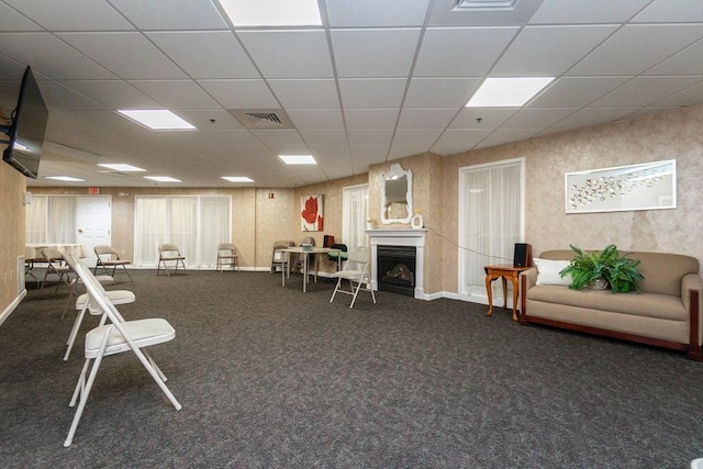 misc room with dark colored carpet and a paneled ceiling