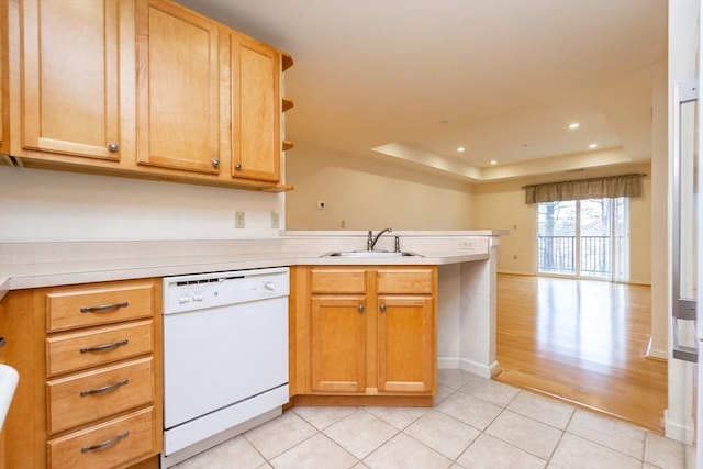 kitchen featuring dishwasher, sink, a raised ceiling, kitchen peninsula, and light tile patterned floors