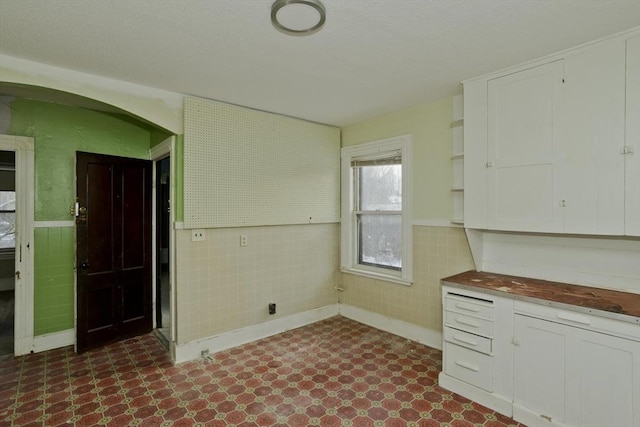 kitchen featuring white cabinetry and tile walls