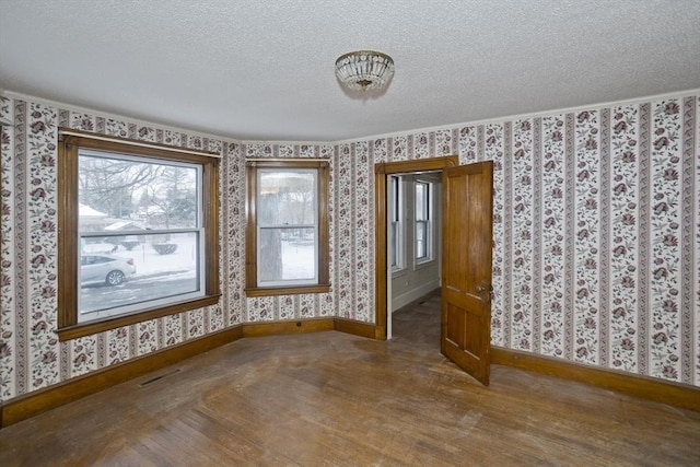 unfurnished room with hardwood / wood-style flooring and a textured ceiling