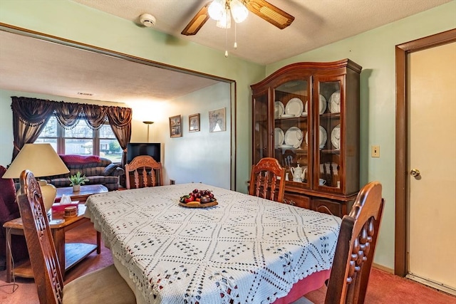 carpeted dining room with ceiling fan