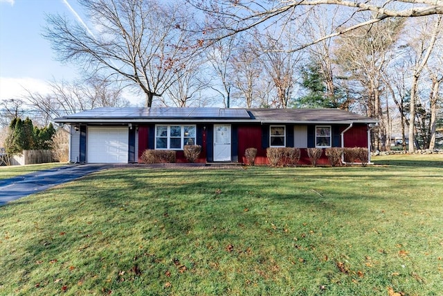 single story home featuring solar panels, a garage, and a front yard