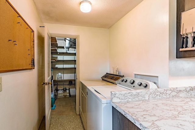 laundry area with separate washer and dryer and a textured ceiling