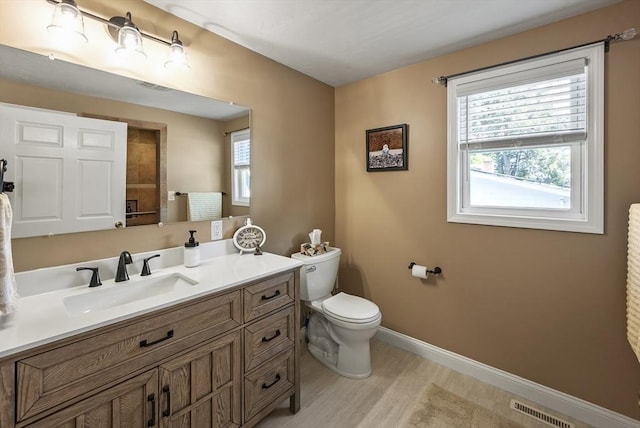 bathroom featuring toilet, baseboards, vanity, and wood finished floors