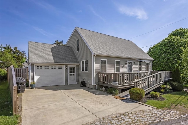 view of front of home featuring concrete driveway, an attached garage, a wooden deck, and a shingled roof
