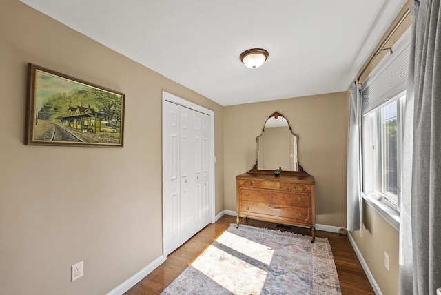 bedroom with wood finished floors, baseboards, and a closet