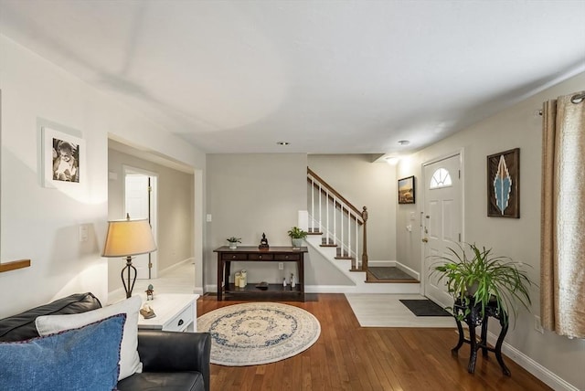 living room with stairs, wood-type flooring, and baseboards