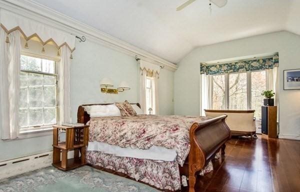 bedroom with ornamental molding, vaulted ceiling, a ceiling fan, a baseboard radiator, and wood finished floors