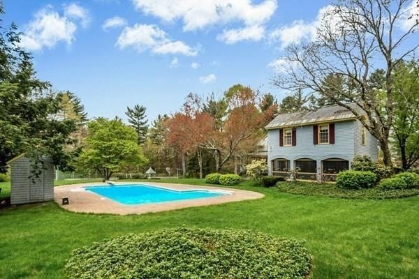 outdoor pool with an outdoor structure and a lawn