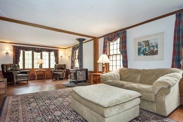 living room featuring a wood stove, ornamental molding, and wood finished floors