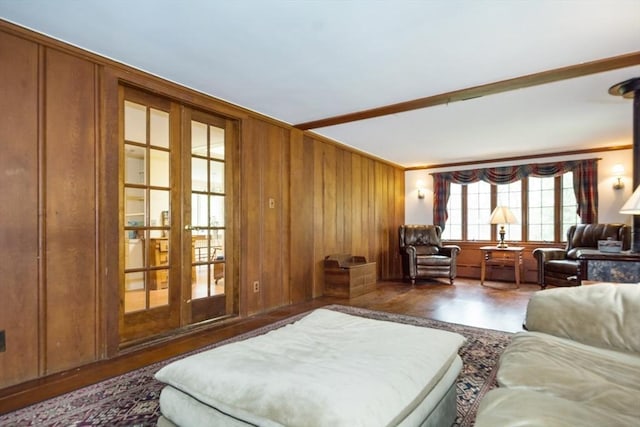 living area featuring wood walls, french doors, crown molding, and wood finished floors