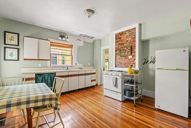 31 Boylston St, Boston, MA 02130 - kitchen with white appliances, light wood-style flooring, white cabinets, light countertops, and a sink