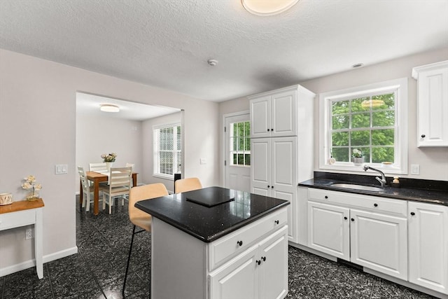 48 Finch Rd Unit 2, Raynham, MA 02767 - kitchen featuring white cabinetry, a center island, granite tiled floors, a textured ceiling, and a kitchen breakfast bar
