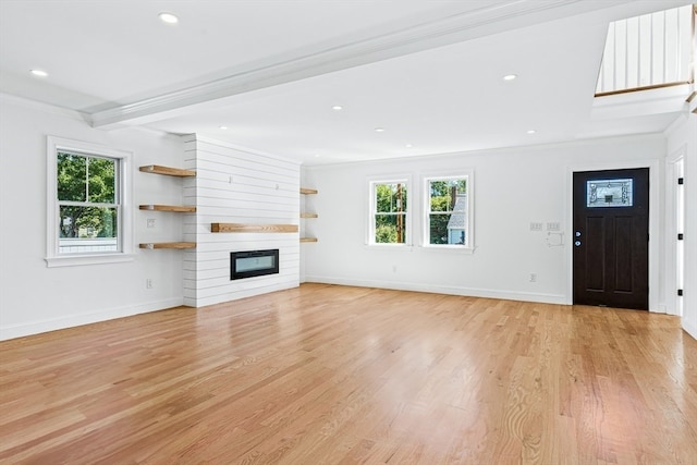 unfurnished living room featuring crown molding, light hardwood / wood-style flooring, beam ceiling, and a large fireplace