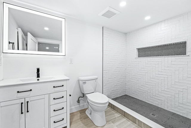 bathroom featuring vanity, toilet, wood-type flooring, and tiled shower