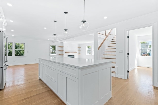 kitchen with plenty of natural light, a kitchen island, decorative light fixtures, and light wood-type flooring