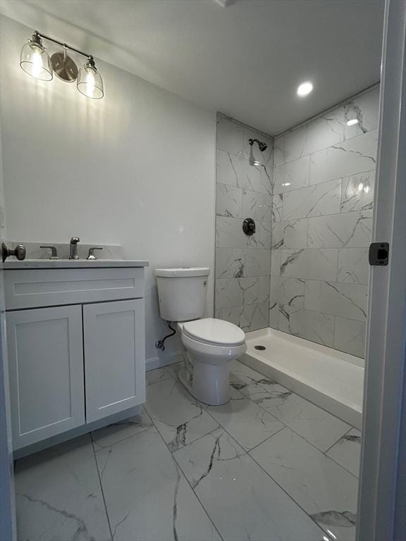 bathroom with vanity, toilet, and a tile shower