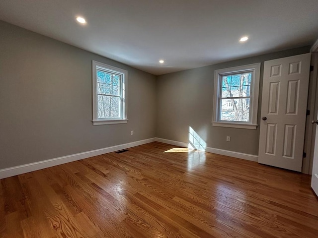 unfurnished room featuring wood-type flooring and a healthy amount of sunlight