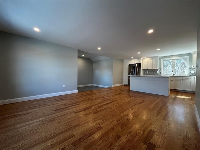 kitchen with dark wood-type flooring, white cabinetry, tasteful backsplash, a kitchen island, and black refrigerator with ice dispenser