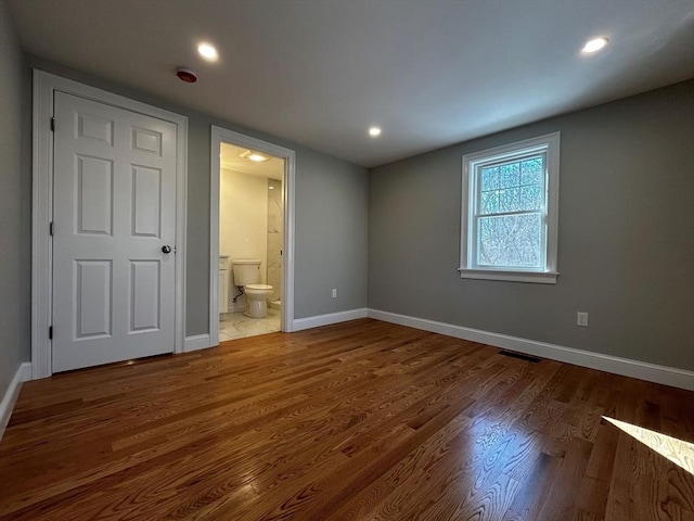 unfurnished bedroom featuring hardwood / wood-style flooring and ensuite bathroom