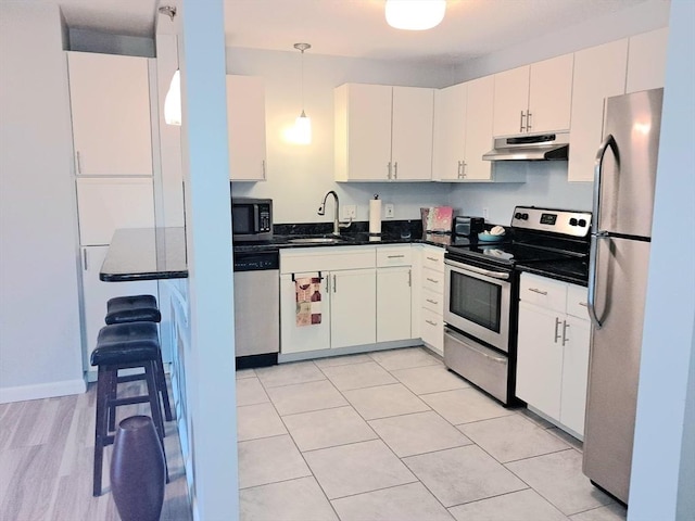 300 Candlewood Park Unit 32, Nashua, NH 03062 - kitchen with under cabinet range hood, appliances with stainless steel finishes, a sink, dark countertops, and hanging light fixtures