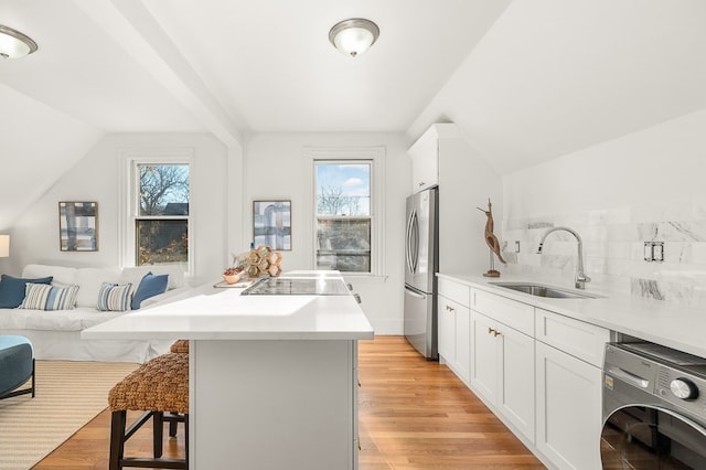 kitchen with sink, a kitchen island, a healthy amount of sunlight, and washer / dryer