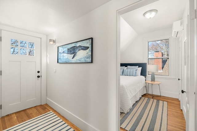 entrance foyer with lofted ceiling, light hardwood / wood-style flooring, a wall mounted AC, and a healthy amount of sunlight