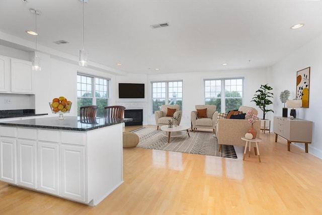 kitchen featuring light wood-type flooring, visible vents, plenty of natural light, and a fireplace