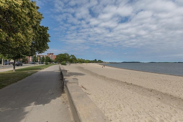 view of road featuring sidewalks, a beach view, and a water view