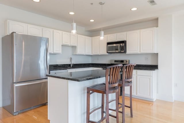 kitchen with a sink, visible vents, appliances with stainless steel finishes, and white cabinets