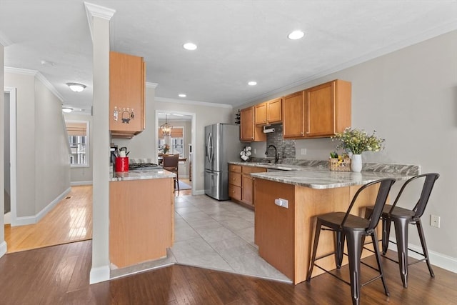 10 Sprucewood Ln Unit 10, Worcester, MA 01606 - kitchen featuring stainless steel refrigerator with ice dispenser, a peninsula, crown molding, a breakfast bar area, and brown cabinetry