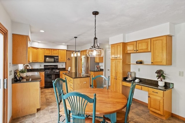 kitchen featuring black appliances, a sink, dark countertops, a kitchen island, and recessed lighting