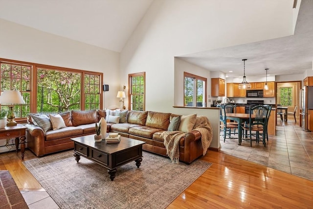 living room featuring high vaulted ceiling and light wood-style flooring