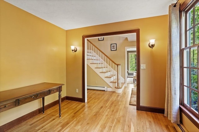 entryway with baseboard heating, stairway, light wood finished floors, baseboards, and healthy amount of natural light
