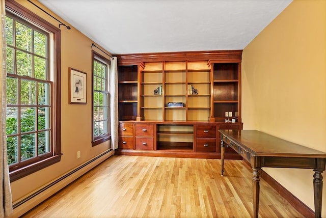 unfurnished office with a baseboard radiator, light wood-type flooring, and baseboards