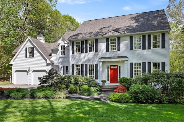 colonial home with a front lawn, concrete driveway, and a shingled roof