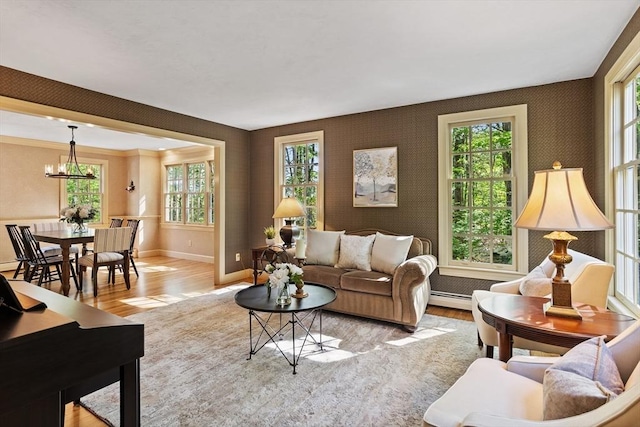living room featuring wood finished floors, baseboards, a chandelier, and plenty of natural light