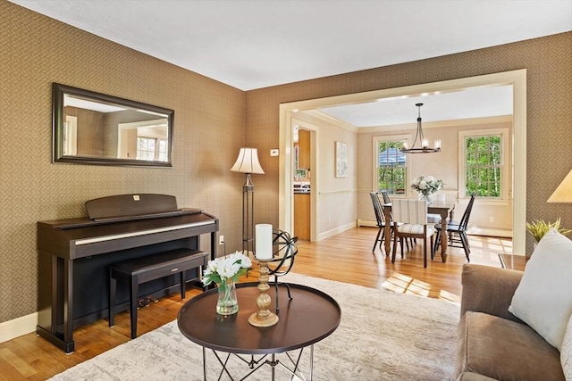 living room with wallpapered walls, wood finished floors, baseboards, and a chandelier