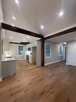 unfurnished living room with sink, lofted ceiling, and light hardwood / wood-style floors