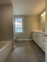 bathroom featuring tile patterned floors, vanity, a tub to relax in, and toilet