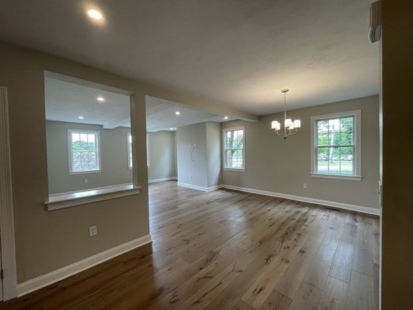 unfurnished room with an inviting chandelier and wood-type flooring