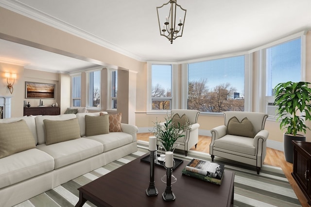 living room featuring ornate columns, ornamental molding, light hardwood / wood-style flooring, and an inviting chandelier