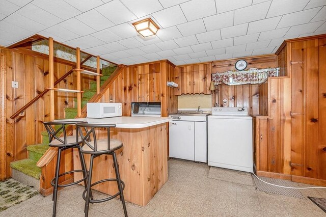101 Harold Ave, Dracut, MA 01826 - kitchen featuring white microwave, wooden walls, washer and dryer, light countertops, and a breakfast bar