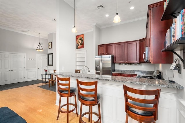 215 Harvard St Unit 40, Medford, MA 02155 - kitchen with appliances with stainless steel finishes, a peninsula, ornamental molding, light stone counters, and light wood-style flooring