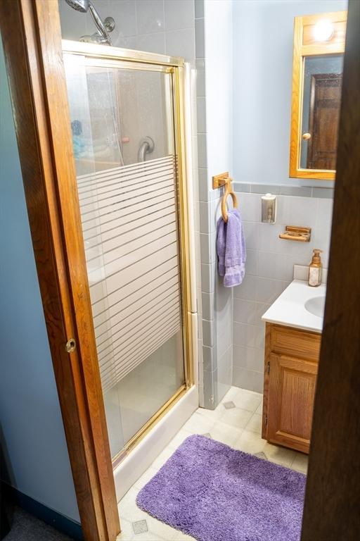 89 Audubon Ave, Braintree, MA 02184 - full bathroom with a shower stall, vanity, tile walls, wainscoting, and tile patterned floors