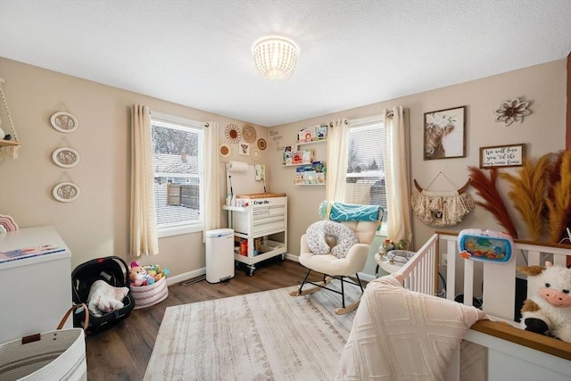 bedroom with dark hardwood / wood-style floors, a crib, and multiple windows