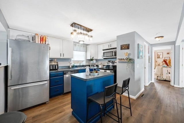 kitchen with blue cabinets, white cabinets, stainless steel appliances, and a kitchen island