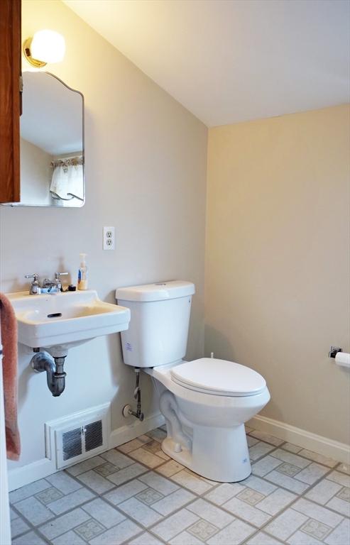 half bathroom featuring visible vents, a sink, baseboards, and toilet
